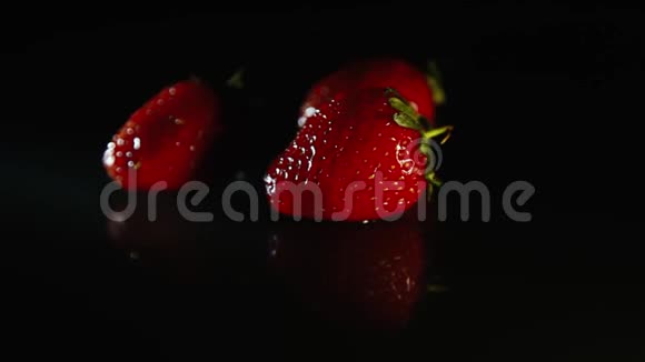 三颗草莓在一缕阳光下美丽地躺在黑桌上视频的预览图