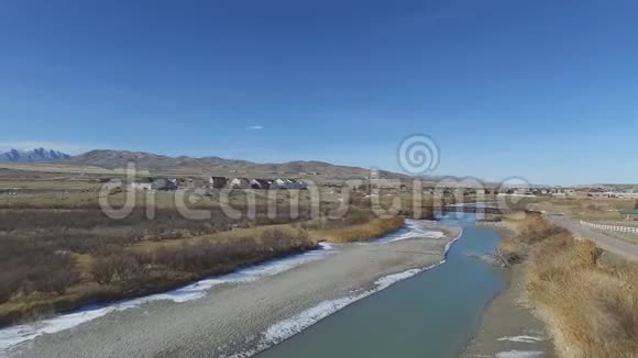 俯瞰一条懒洋洋的河流和一座跨河建造房屋的桥梁视频的预览图