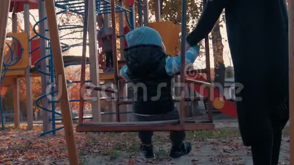 小男孩在公园的儿童操场上摇摆快乐的孩子在户外玩得很开心视频的预览图