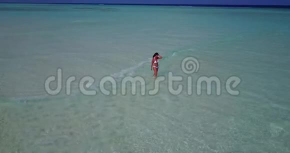 在阳光明媚的热带沙洲上一位年轻美丽的女士在沙滩上观看马尔代夫白色沙滩视频的预览图