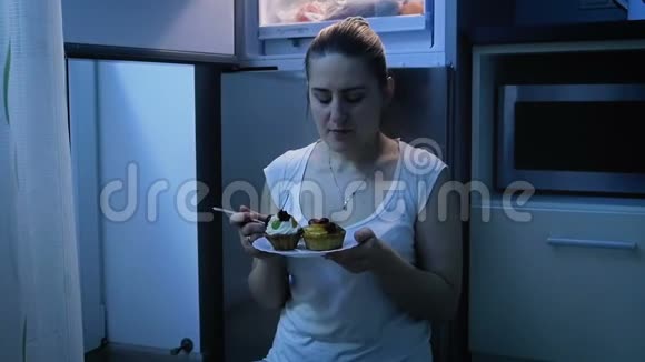 夜间在冰箱附近吃蛋糕的饥饿妇女慢动作视频视频的预览图