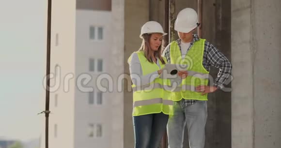 建筑工人男女戴头盔讨论房屋建筑方案相互转告视频的预览图