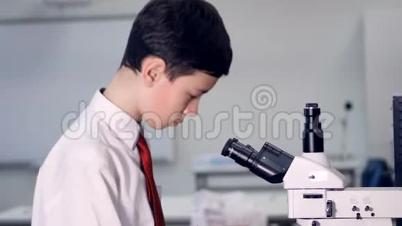 一个男孩化学家看着显微镜视频的预览图