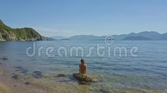 在浅海的石头上坐着的一个女孩视频的预览图