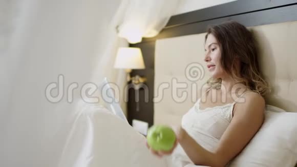 有魅力的女人在床上使用平板电脑在床上辗转绿苹果视频的预览图