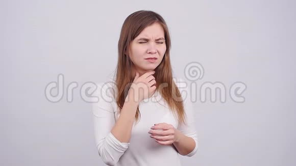 一个年轻的女人在灰色背景下喉咙痛视频的预览图