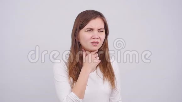 一个年轻的女人在灰色背景下喉咙痛视频的预览图