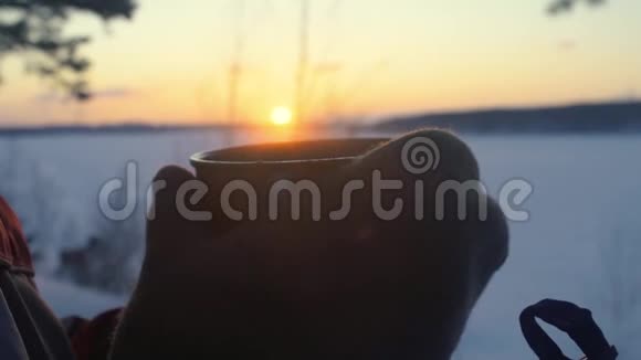 日落时分这个旅游女孩正在雪白的冬林里用保温瓶喝茶视频的预览图