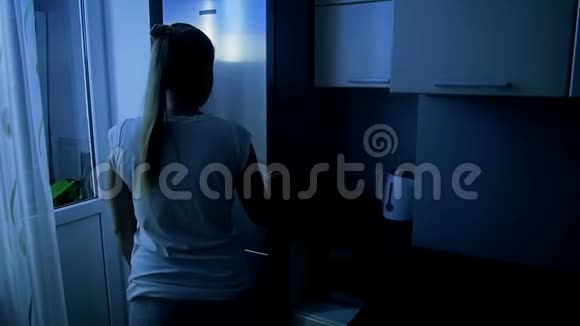 年轻女人从冰箱里拿苹果的慢镜头女孩在晚上吃饭视频的预览图