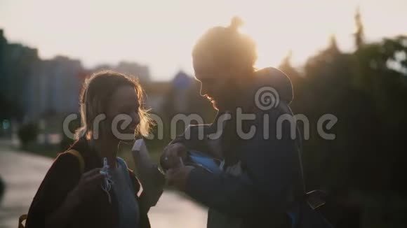 傍晚日落时分年轻漂亮的夫妇在市中心散步一男一女抱着盒子视频的预览图