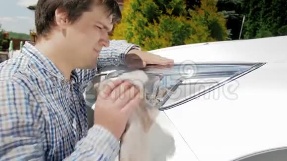 4k视频年轻人用布擦洗车前灯视频的预览图