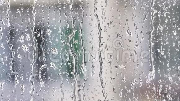 窗户玻璃表面有模糊建筑背景的雨滴4k电影慢动作视频的预览图