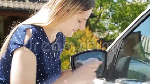 4k视频年轻微笑的女人用布清洁汽车侧镜视频的预览图