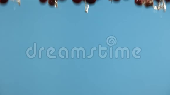 成熟的樱桃落在蓝色背景上的水中液态红樱桃浆果视频的预览图