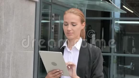 女商人散步和使用平板电脑在线浏览视频的预览图