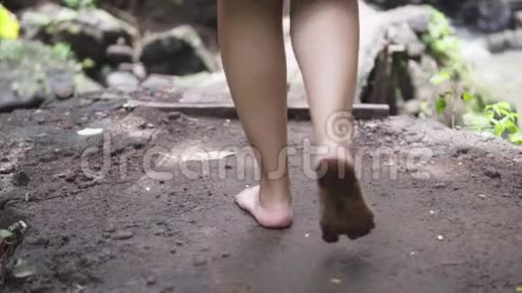 行走的女人穿着一件连衣裙赤着脚踏在潮湿的地面上走在丛林森林里视频的预览图
