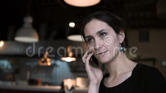 布鲁内特漂亮的女人坐在咖啡馆里和朋友用手机聊天有魅力的女性使用智能手机视频的预览图