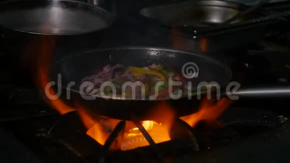 专业厨师兼消防用明火在黑暗的背景下烹饪蔬菜和食物视频的预览图