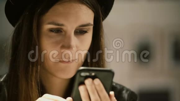 年轻美丽的女人在画廊戴帽子和使用智能手机的肖像学生女性独自度过闲暇时光视频的预览图