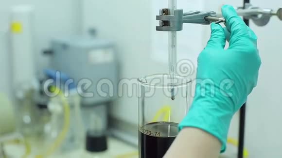 油库检测中心的人员用生物燃料将温度计装入烧杯中视频的预览图