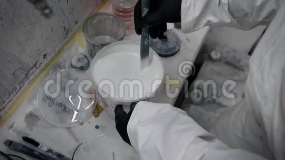 一名工人在室内罐内用手搅拌白色油漆视频的预览图