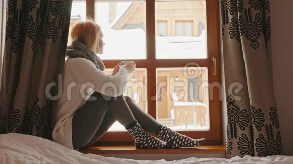 在冬天的窗户里端着一杯茶的女人视频的预览图