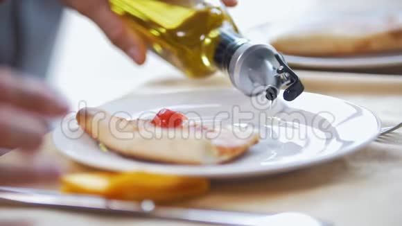 女性手在盘子里倒油在餐馆里吃披萨视频的预览图