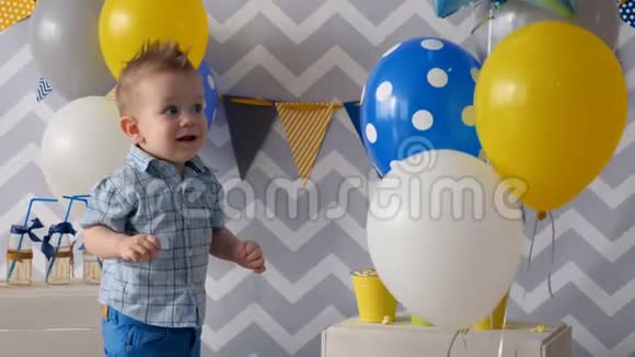 一个蹒跚学步的孩子小心翼翼地摸着五颜六色的气球视频的预览图
