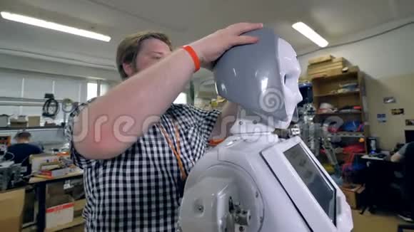 一位年轻的工程师检查机器人塑料头发的合身程度视频的预览图