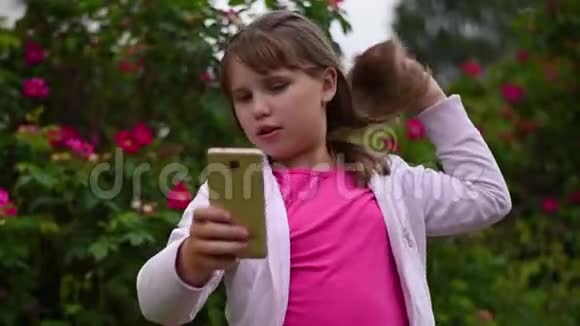 一个金发的欧洲女孩在智能手机上拍照视频的预览图