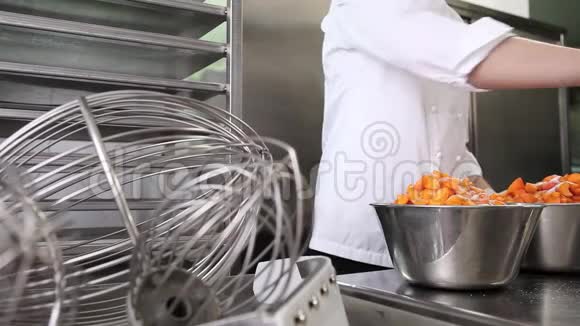 手把糕点厨师把糖铺在杏子水果上在工业厨房准备果酱视频的预览图