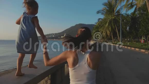 年轻的母亲带着小女儿在海边慢跑视频的预览图