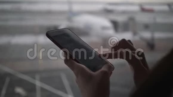 女子在机场候机楼使用手机等待登机视频的预览图