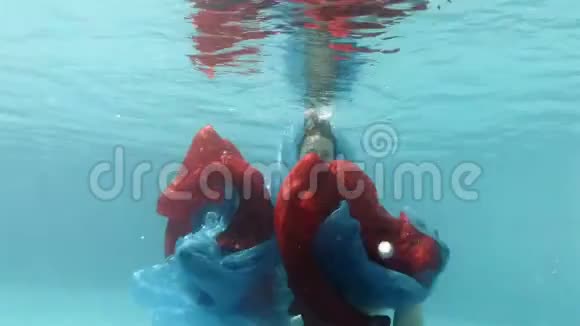 这个十几岁的女孩穿着一件连衣裙在游泳池里水下游泳玩着一件红色和蓝色的布视频的预览图