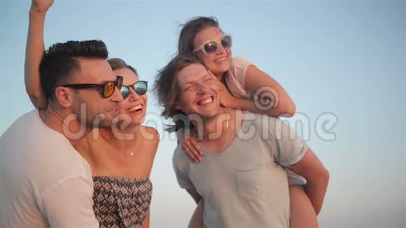 四个快乐的微笑男女在夏天的假期里一起在海边享受日落视频的预览图