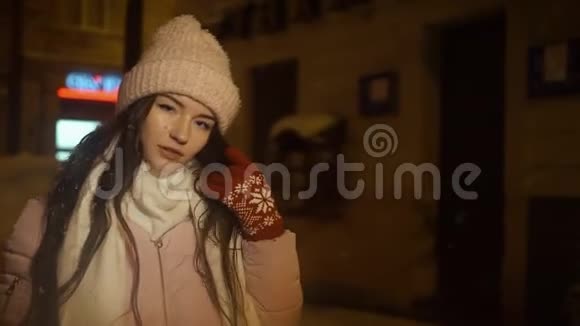 在下雪的天气里美丽迷人的女孩在晚上穿过城市的街道女孩正走进来视频的预览图