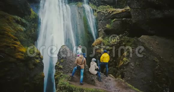这群游客在山顶上休息在冰岛的Gljufrabui瀑布上观看视频的预览图