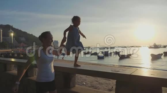 年轻的母亲带着小女儿在海边慢跑视频的预览图