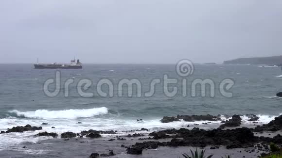 波浪在岩石海岸盘旋船在地平线上视频的预览图