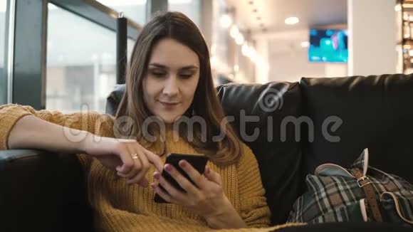 年轻迷人的女人坐在咖啡馆里使用带有触摸屏的智能手机女孩午餐休息一下视频的预览图
