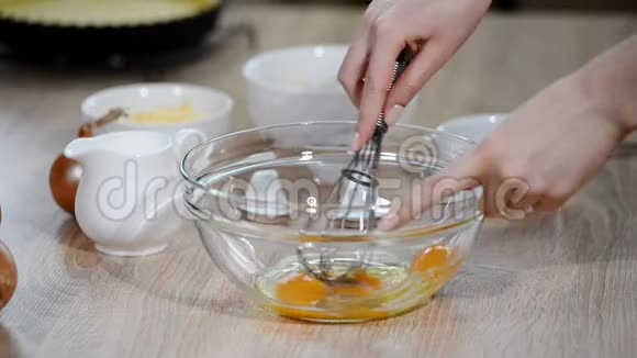 女厨师在厨房餐桌上用玻璃碗搅拌鸡蛋视频的预览图