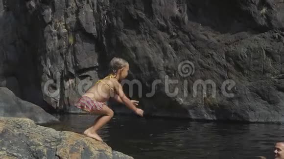 小可爱的女孩在湖水中向妈妈跳来跳去视频的预览图