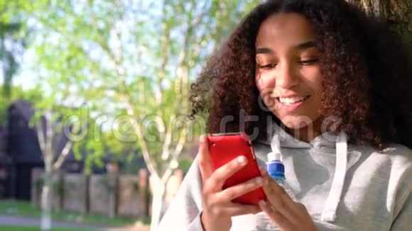 一个非洲裔美国少女用手机靠在树上视频的预览图