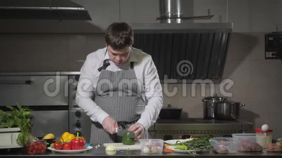 年轻的厨师在白色的切割板特写上切割辣椒在餐厅厨房做饭视频的预览图