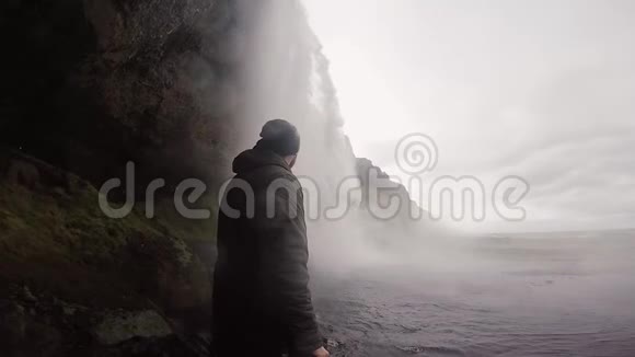 人在gopro相机上拍摄冰岛美丽而强大的Seljalandsfoss瀑布溅在岩石上的水视频的预览图