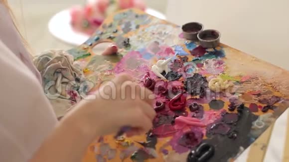 这位艺术家用画笔和特写在调色板上混合油画视频的预览图