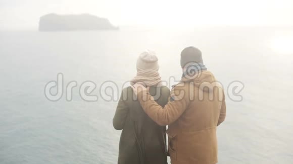 在寒冷的雾天年轻男女站在海边欣赏美丽的景色视频的预览图