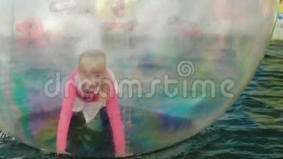 一个女孩在水上漂浮的透明碗里玩耍游乐园娱乐视频的预览图