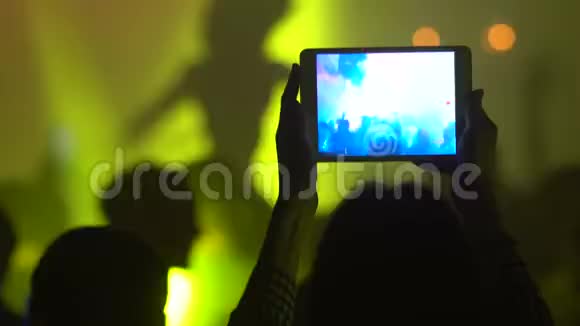 女人用平板电脑录制现场音乐会视频的预览图