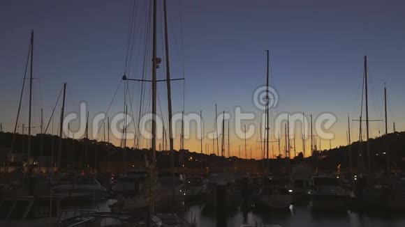 黄昏时分在码头上的一排排船只在日落的天空中视频的预览图